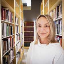 woman with shoulder length blonde hair wearing white shirt standing in library stacks